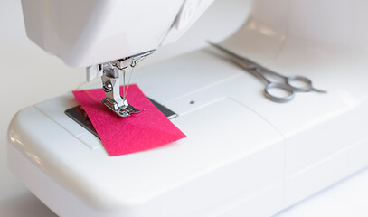 sewing machine with pink fabric in working, equipment for sewing,  scissors