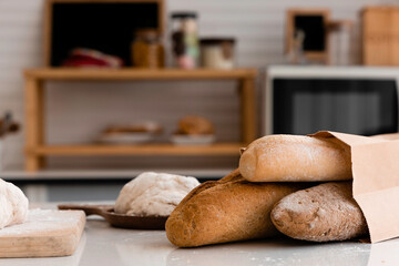 loaf of bread in paper bags and fresh dough on a table in the kitchen