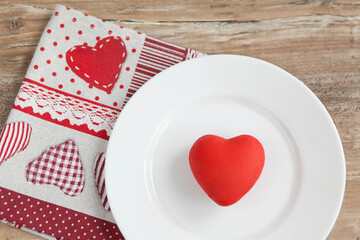 
Love concept. The symbolic red heart lies on a white plate on the table.