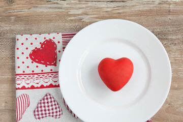 Obraz na płótnie Canvas Love concept. The symbolic red heart lies on a white plate on the table.