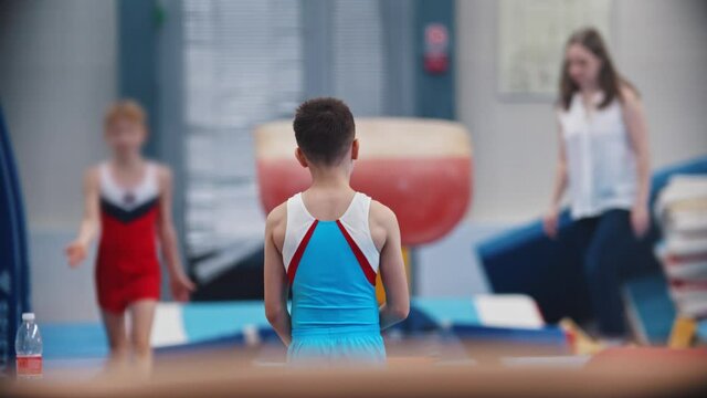 A little gymnastics boy running up jumping over the barrier
