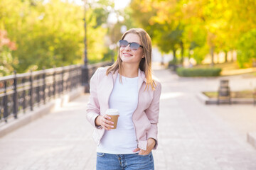 Portrait of a young, happy and pretty blonde girl with a cup of coffee in her hands