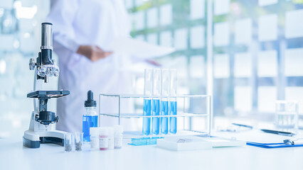 Medical or scientific researcher or man doctor looking at a test tube of clear solution in a...