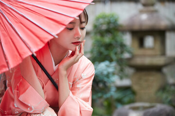 赤い和傘を持った着物姿の若い女性