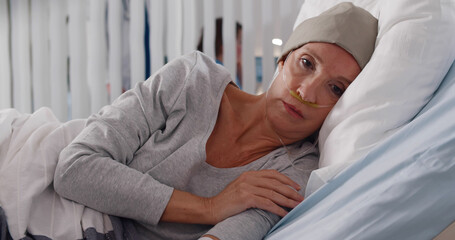 Depressed and hopeless cancer patient woman wearing head scarf in hospital.
