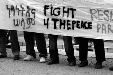 Grayscale shot of people holding a paper with the fight for peace on it during the protest