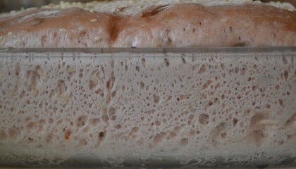 Sourdough for bread in a glass form.