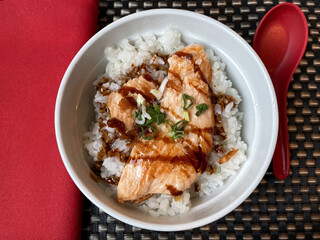 Japanese food rice and salmon teriyaki sauce in white bowl with red napkin and spoon top view 