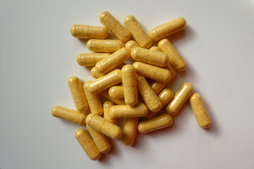 Fistful of orange cellulose capsules of multivitamins from above