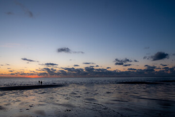 View of the setting sun shining on the Sea and reflected on the beach, clouds with sun-shining edges. Landscape. High quality photo showing concept of freedom and dreams