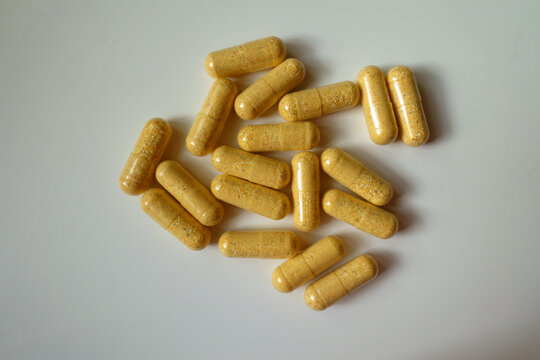 Top view of handful of orange cellulose capsules of multivitamins