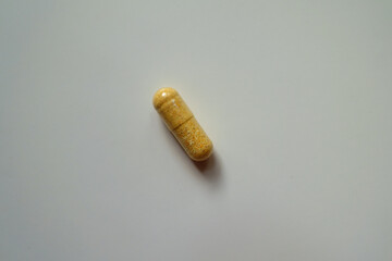 Top view of one orange cellulose capsule of multivitamins