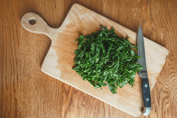 Cut sorrel leaves and a knife on a wooden board. Chopped greens for cooking
