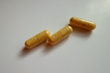 Closeup of three orange cellulose capsules of multivitamins