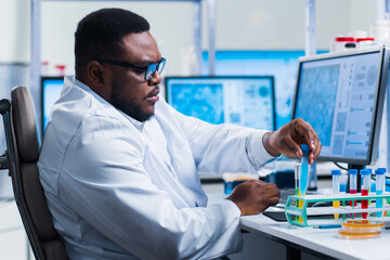 Naklejka na ściany i meble Professional African-American scientist is working on a vaccine in a modern scientific research laboratory. Genetic engineer workplace. Future technology and science.