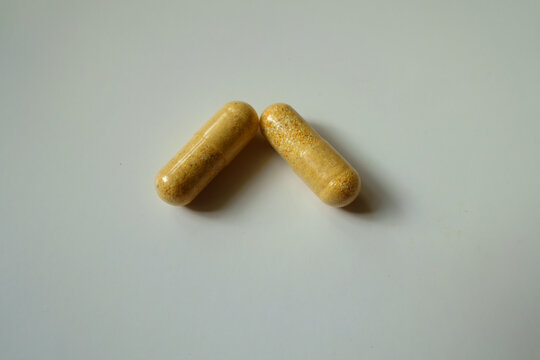Close view of two orange cellulose capsules of multivitamins