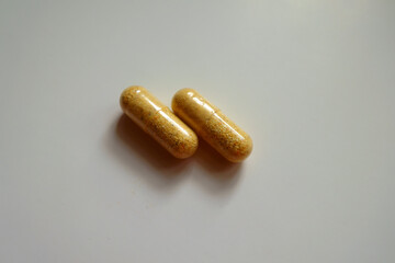 Pair of orange cellulose capsules of multivitamins