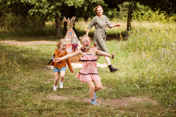 Daughters are playing outdoors with their mom next to wigwam decoration. © Natalia