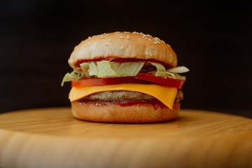 burger with cheese and tomato on a wooden plank
