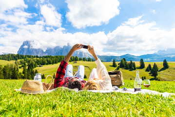 Young couple taking a selfie holding smart phone mobile lying on the grass at park - Tourist at...