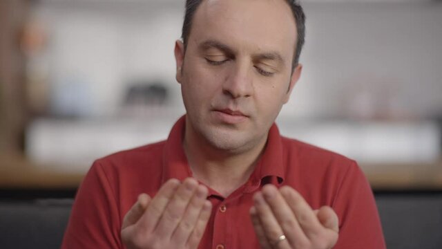 Young Muslim man at home with open palms praying to God.Praying man.Close up.