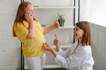 Happy fat girl and nutritionist rejoices about good result of being on a diet