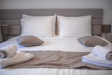 Modern bedroom with white bed. Bed maid-up with clean white pillows and bed sheets in beauty bedroom. Close-up. Interior background. Modern bedroom with  bed and set of white color tone pillows