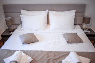 Modern bedroom with white bed. Bed maid-up with clean white pillows and bed sheets in beauty bedroom. Close-up. Interior background. Modern bedroom with  bed and set of white color tone pillows