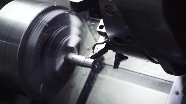 Hardened steel cutter cuts metal part on machine. Metal shavings fly in slow motion