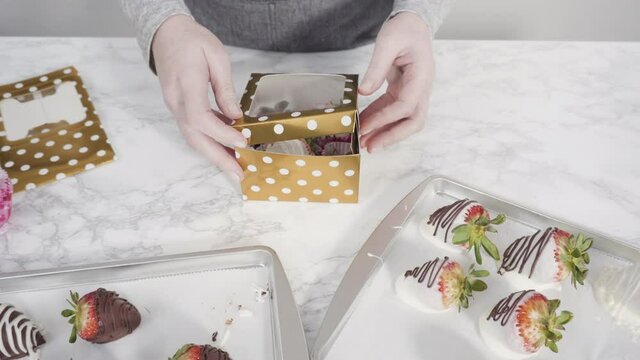 Step by step. Packaging chocolate dipped strawberries into a paper box for a gift.