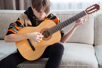 Boy playing guitar at home, online lesson. High quality video