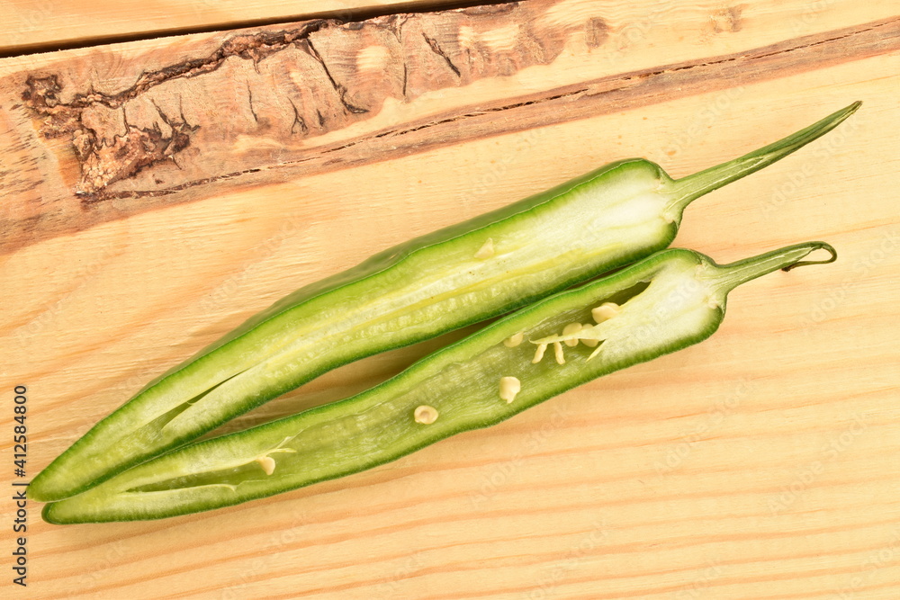 Wall mural two half pods of ripe organic, spicy green hot pepper, close-up, on a wooden table.