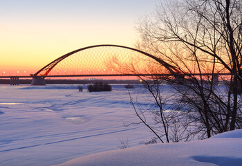 Winter sunrise on the Ob river. Bugrinsky automobile bridge on the frozen snow bank in Novosibirsk