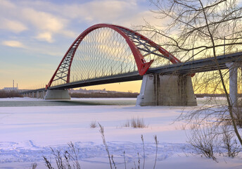 Winter morning on the Ob. The arch of the Bugrinsky automobile bridge on the frozen river bank in Novosibirsk