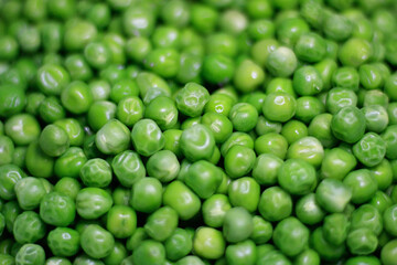 Background of young juicy green peeled peas mound