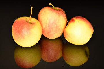 Three ripe organic, juicy, fragrant apples, close-up, on a black background.