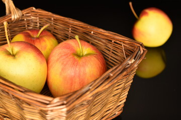 Several ripe organic, juicy, aromatic apples in a basket, close-up, on a black background.