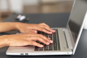 Fototapeta na wymiar Close up image of female elegant hands typing text on the laptop keyboard, businesswoman responding to the client e-mail, buying ordering items online. Internet and modern wireless technology concept