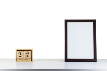 Wooden calendar 27 february with frame for photo on white table and background