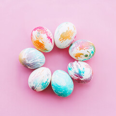 easter eggs painted in bright colors laid out like a flower on a pink background, square frame