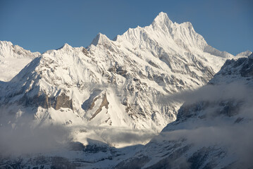 Obraz premium View of the Swiss mountains in winter. Mittelhornin clouds, Schreckhorn and Wetterhorn. Swiss alps in Switzerland Jungfrauregion