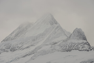View of the Swiss mountains in winter. Eiger in clouds, Monoch and Jungfrau. Swiss alps in Switzerland Jungfrauregion.