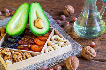 Healthy food. Detox, foods saturated with Omega 3. Avodkado and assorted nuts, dried fruits, on a dark old wooden background