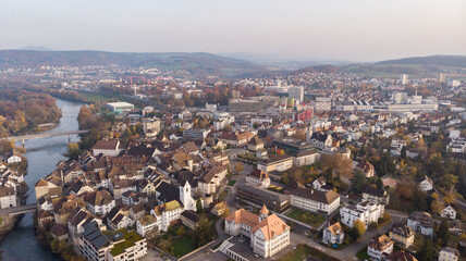 Fototapeta premium Drone view of cityscape Brugg with Aare river, residential and commercial districts, historic old town and casino bridge in canton Aargau in Switzerland. Town situated on feet of Tafeljura.