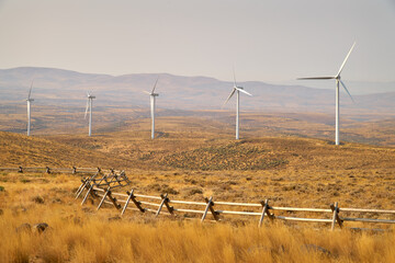 Windfarm Turbine Field. Wind turbines on an agricultural field behind a ranch fence.

