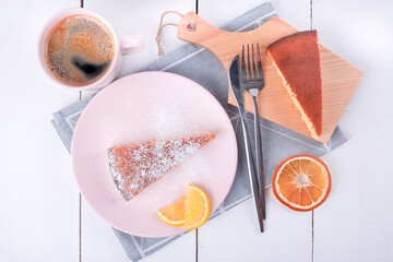 Close-up top view of two pieces of pie on a pink plate and a cutting board with a knife and fork on a folded linen napkin and a mug with coffee. Homemade baking. Selective focus.