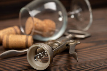 Corkscrew and corks from wine bottles on a wooden table.