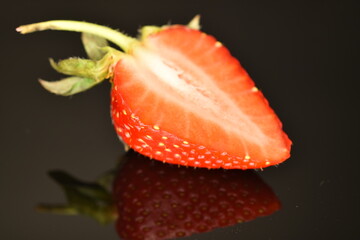 Half a juicy strawberry, close-up, on a black background.