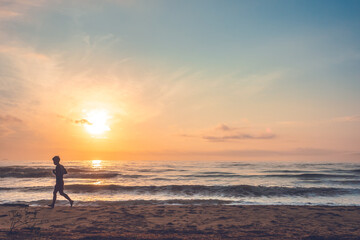 silhouette of jogging man on beach in the morning at sunrise.