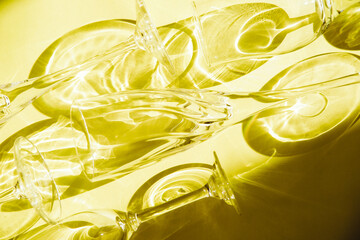 Empty glasses stand on a yellow background, top view. Sunlight is refracted through the glass.